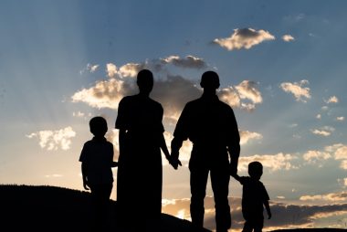 a group of people standing on a hill looking at the sunset
